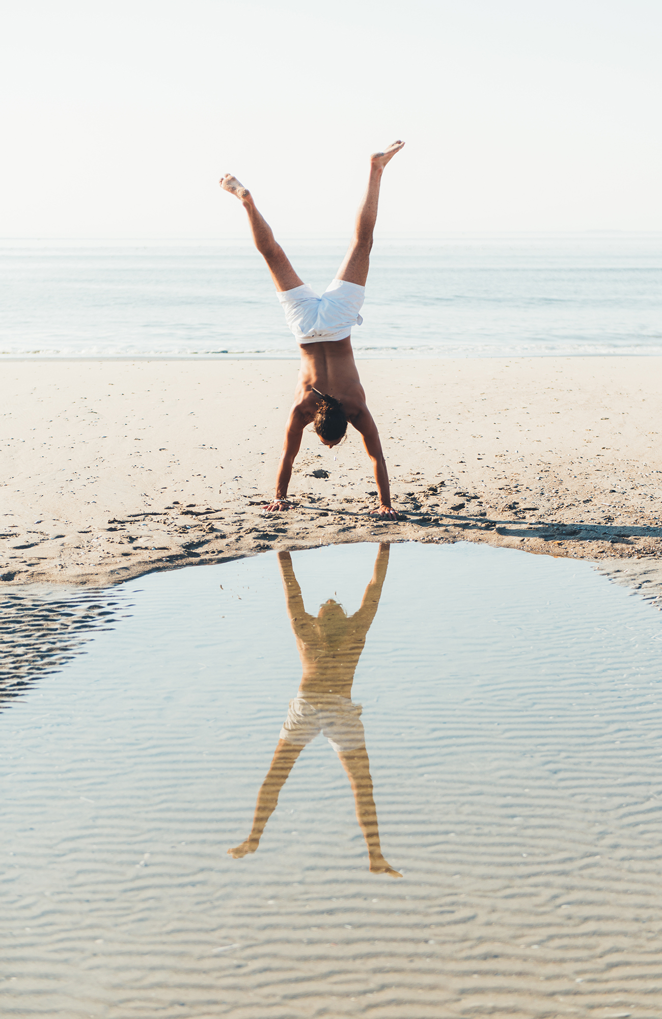 Käsilläseisova mies hiekkarannalla