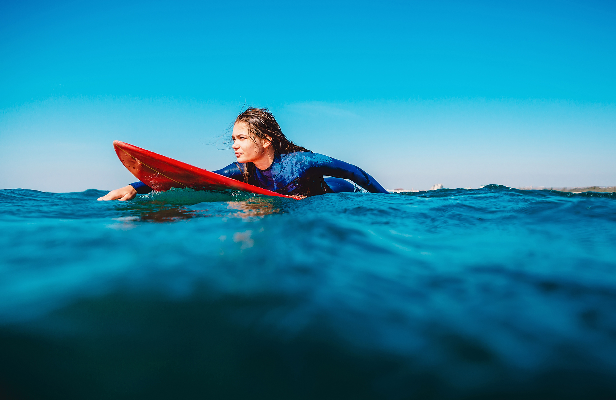 tyttö makaamassa surffilaudan päällä vedessä