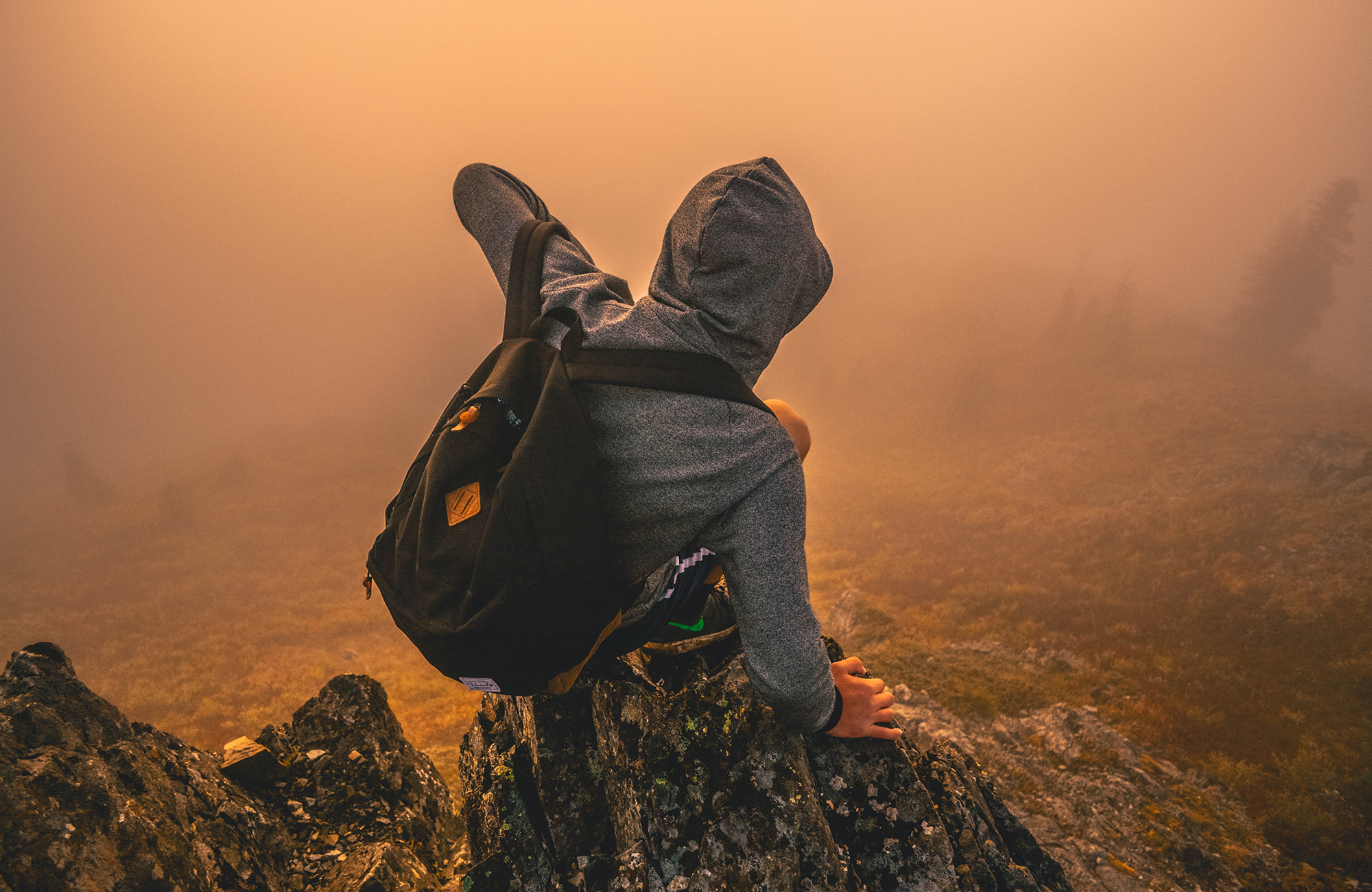 Backpacker sitting on a stone during sunset