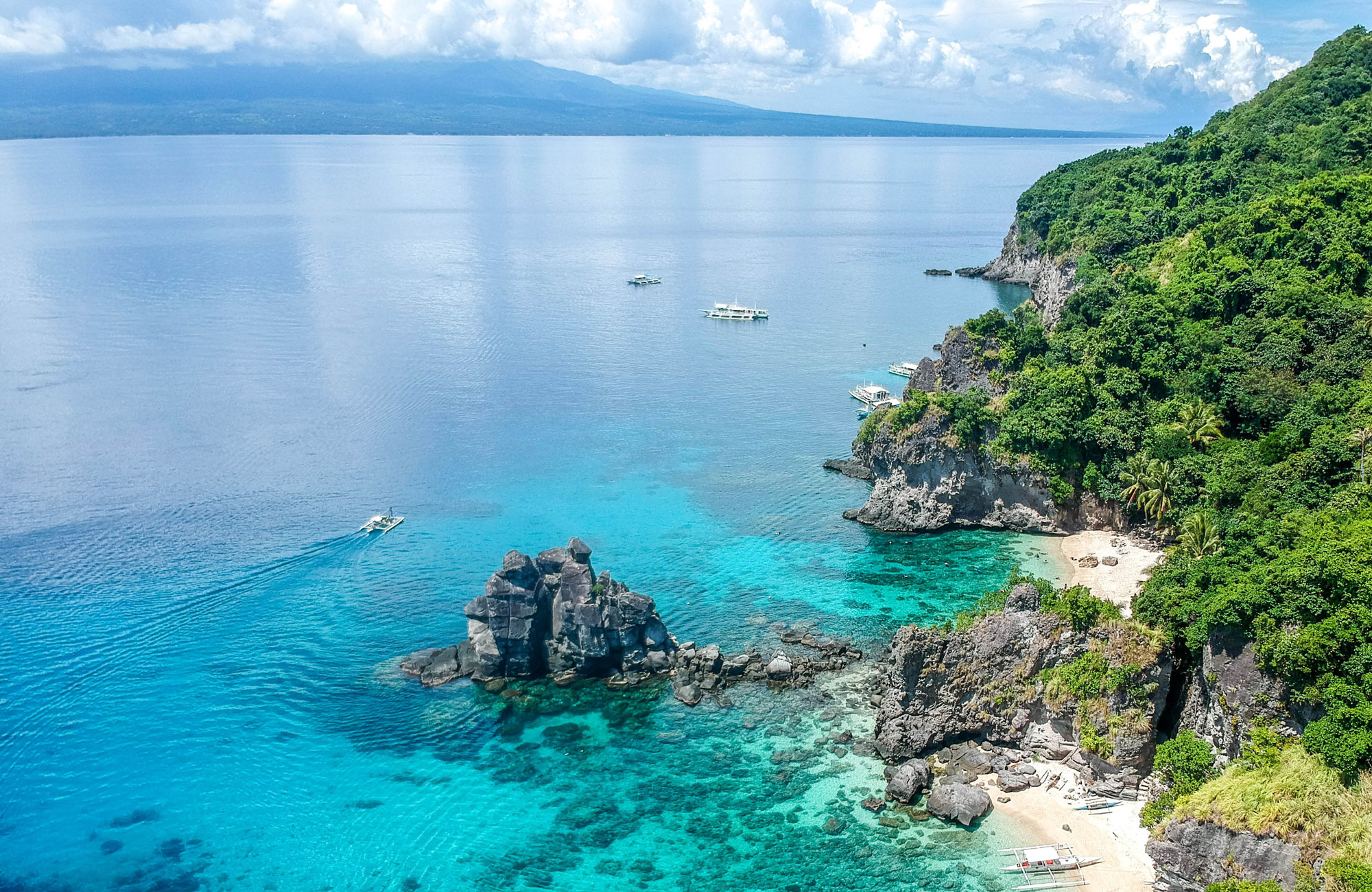 Green oceanside cliffs and very blue water near Dauin on the island of Negros in the Philippines