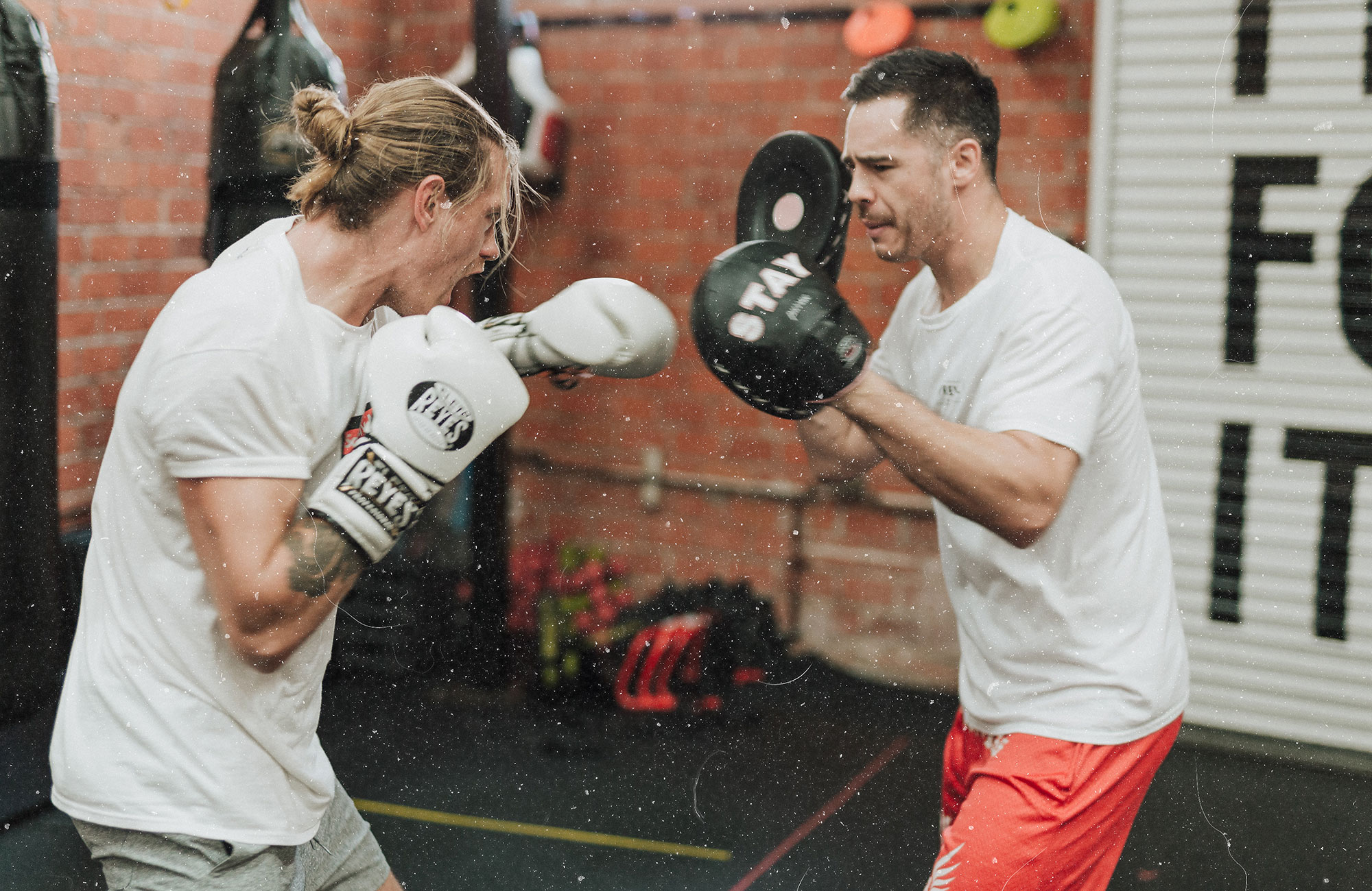 Kaksi miestä nyrkkeilemässä kuntosalilla