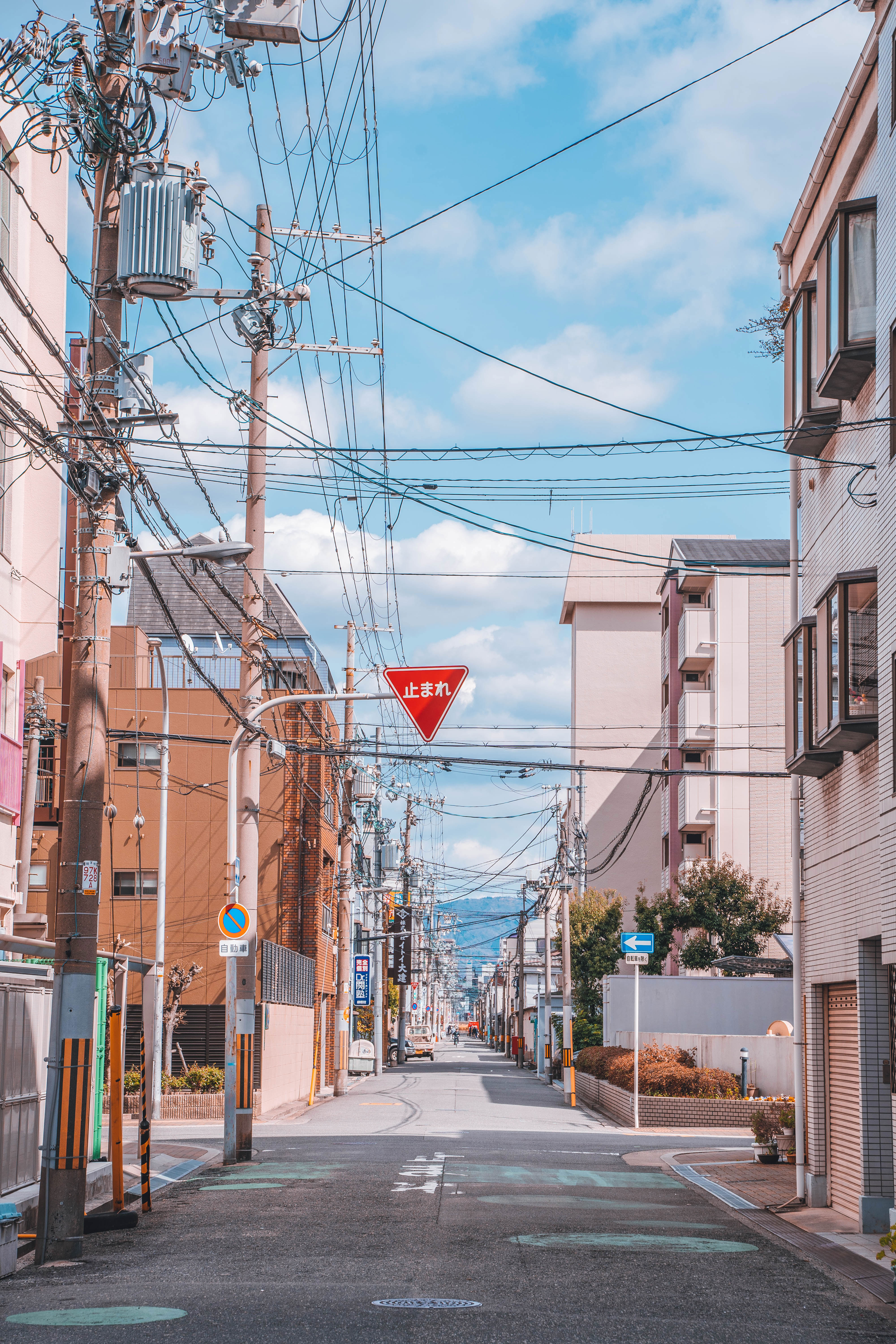 Empty street in Japan with lots of overhead powerlines, as well as some road signs indicating one way streets and more