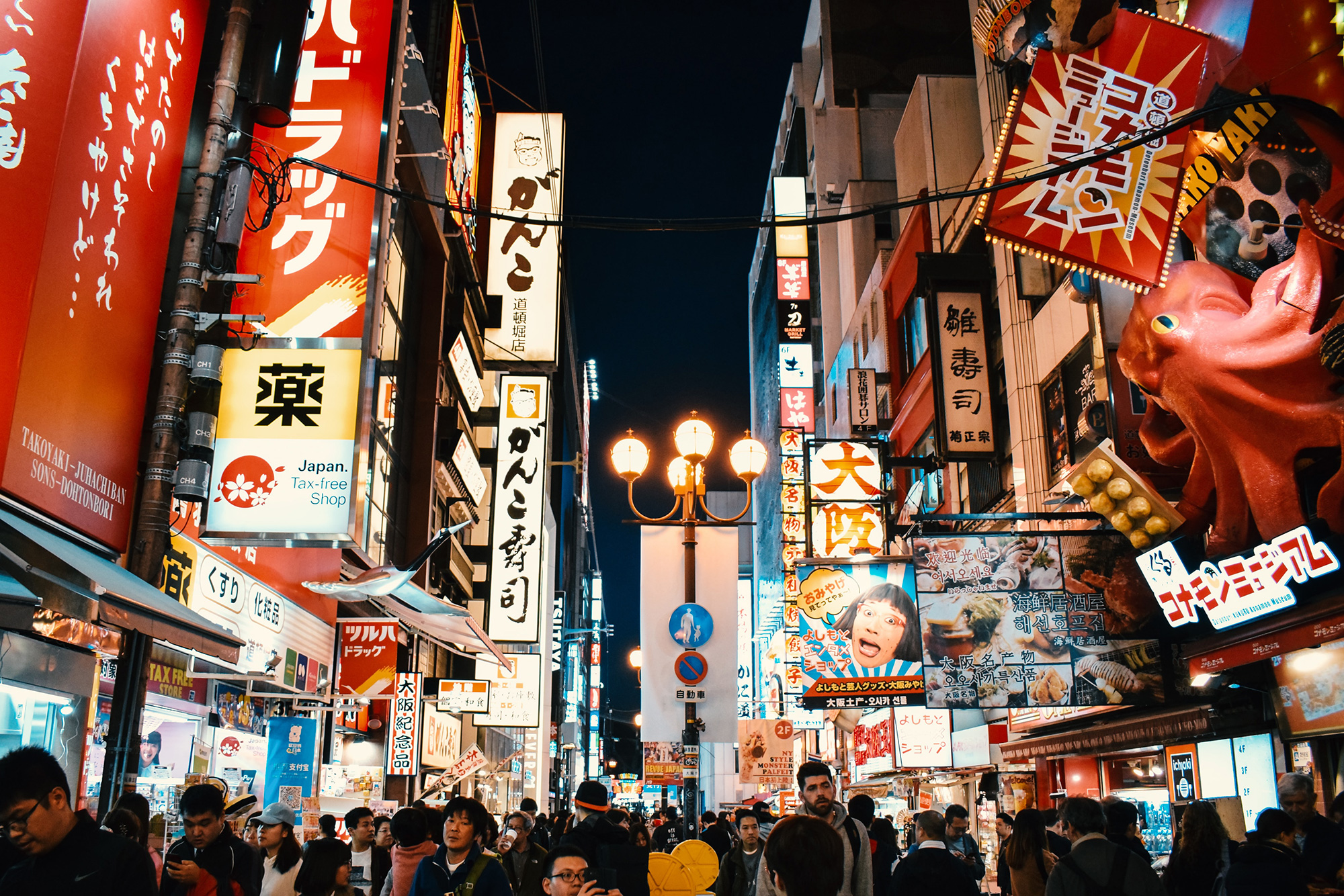 The busy main street in Osaka, with many neon signs and other lights making for a very bright display